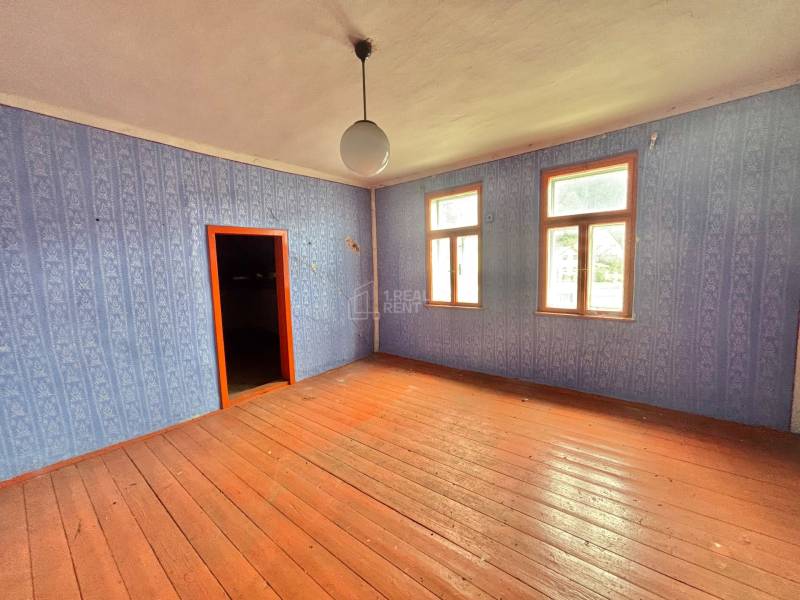 Pokoj v rodinném domě s dřevěnou podlahou a modrou tapetou.