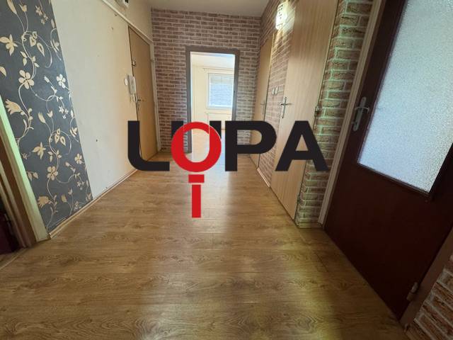 Chodba 3pokojového bytu s laminátovou podlahou a květinovou tapetou.