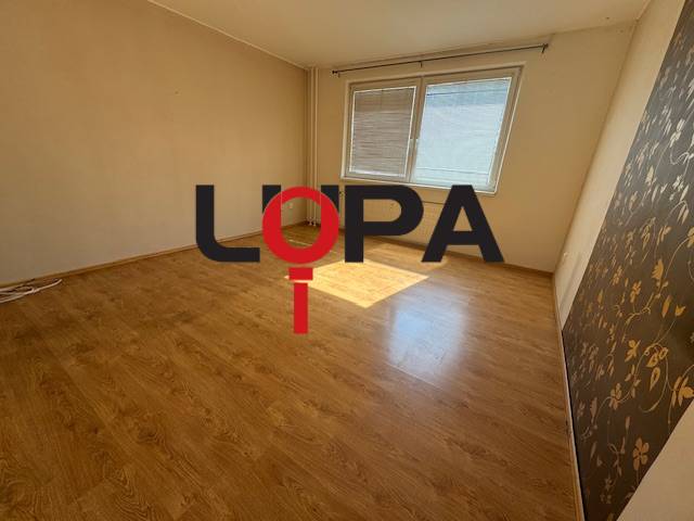 Pokoj se světlou plovoucí podlahou a dvěma okny ve 3-pokojovém bytě.