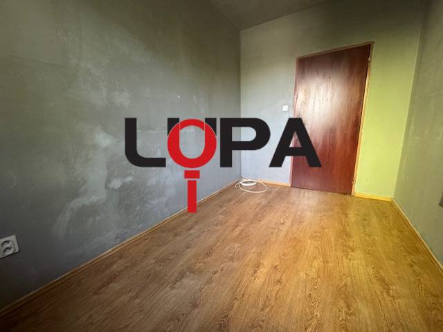Pokoj s dřevěnou podlahou a šedými stěnami ve 3-pokojovém bytě.