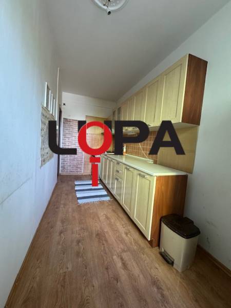 Úzká kuchyňská linka se skříňkami a podlahovou krytinou v 3-pokojovém bytě.