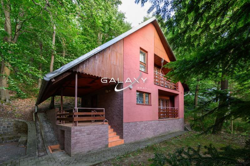 Chata v Ružinej obklopená zelení, s typickou architekturou a dřevěnými detaily.