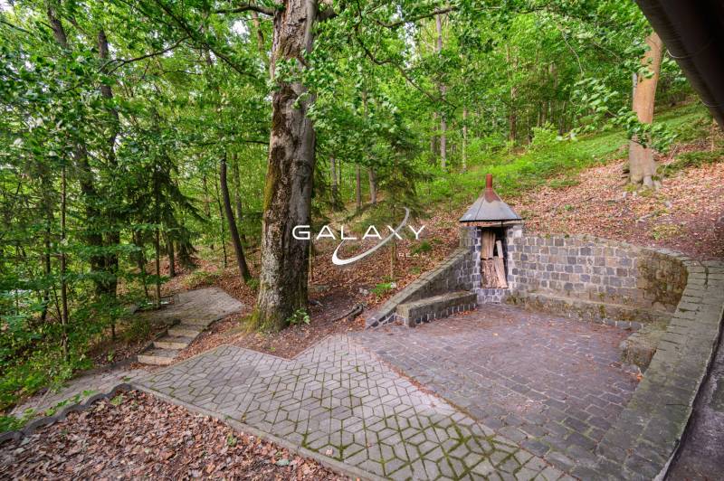 Chatka u Ružiné s kamennou lavičkou a dřevěným přístřeškem na dřevo.