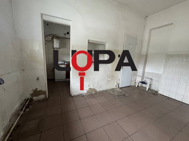 Interiér budovy s poškozenými stěnami a dlaždicemi, vhodný k rekonstrukci.