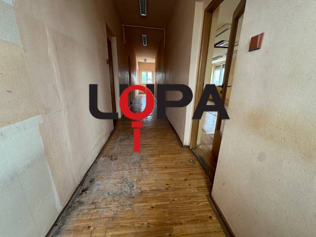 Chodba v budově s dřevěnou podlahou a místnostmi na obou stranách.