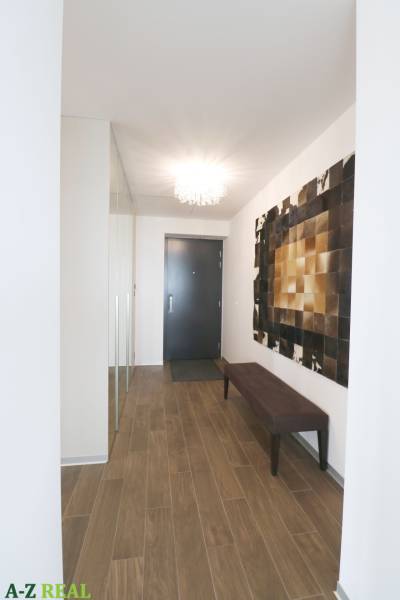 Chodba v 3-pokojovém bytě s podlahou s dřevěným dekorem a elegantním osvětlením.