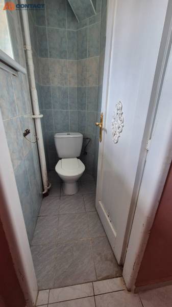 Toaleta obložená dlaždičkami v 3-pokojovém bytě se zavřenými dveřmi.