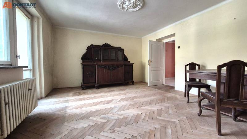 Pokoj ve 3-pokojovém bytě s dřevěným nábytkem a parketovou podlahou.