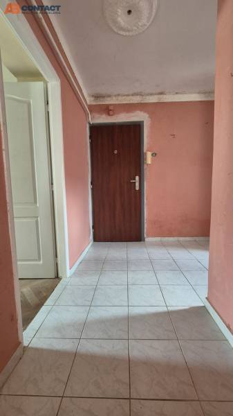 Vstupní chodba se světlou dlažbou a růžovými stěnami ve 3-pokojovém bytě.
