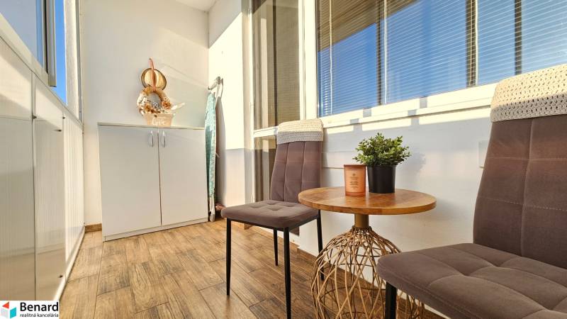 Balkon v 1-pokojovém bytě se dvěma židlemi, stolem a skříní na ukládání.