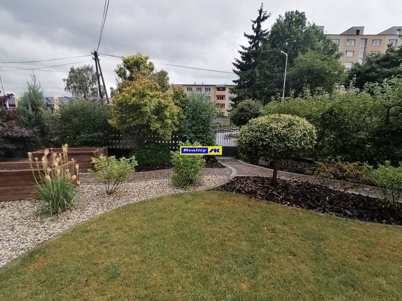 Zahrada rodinného domu na ulici J.Š.Šikuru v Martině s trávníkem a keři.