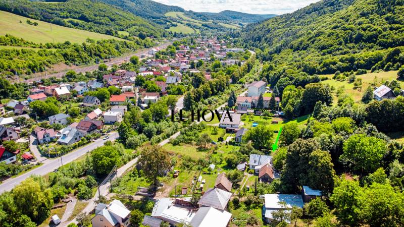 Louky nedaleko železnice, obklopené kopci, zobrazují rozmanitost rodinných domů v Loukách.