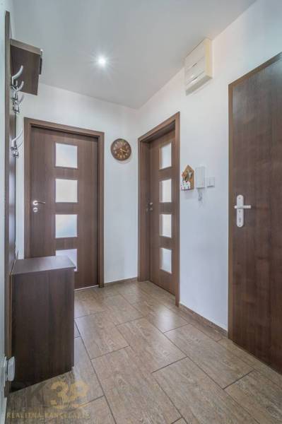 Chodba v 3-pokojovém bytě, obsahuje dveře, věšák a hodiny.