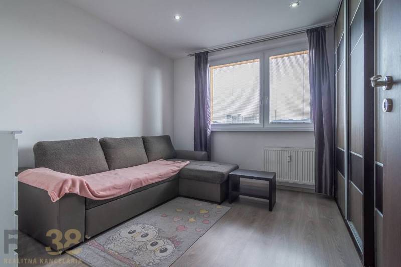 Obývací pokoj ve 3-pokojovém bytě s pohovkou, kobercem a šatní skříní.