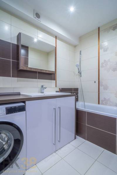 Koupelna ve 3-pokojovém bytě se sprchovým koutem, pračkou a umyvadlovou skříňkou.