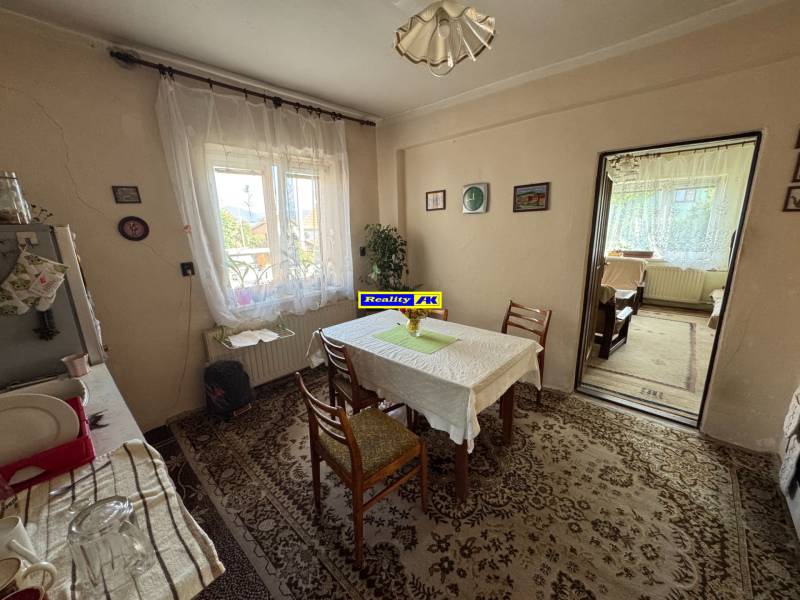 Jídelna v rodinném domě se stolem, židlemi, kobercem a oknem s výhledem.
