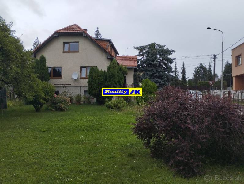 Rodinný dům v Martině, s upravenou zahradou a obklopený stromy a keři.