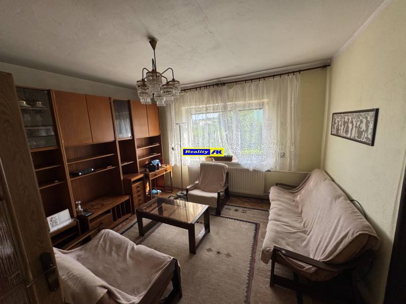 Obývací pokoj v rodinném domě s gaučem, koberec, stěna se skříněmi.