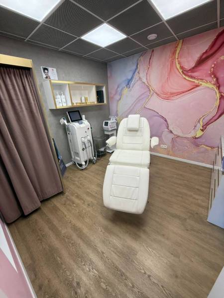 Místnost s kosmetickým křeslem, barevnou stěnou a zařízeními v obchodních prostorách.