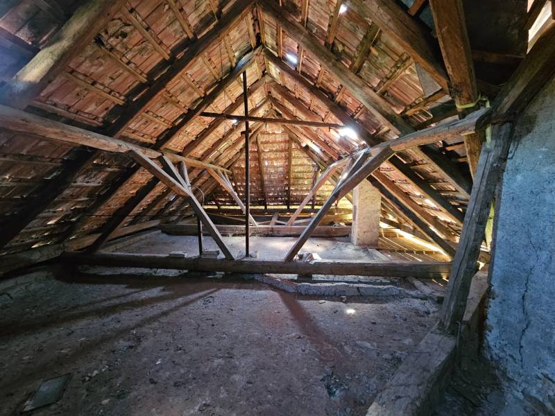 Půda s dřevěnou konstrukcí a střešními taškami v rodinném domě.