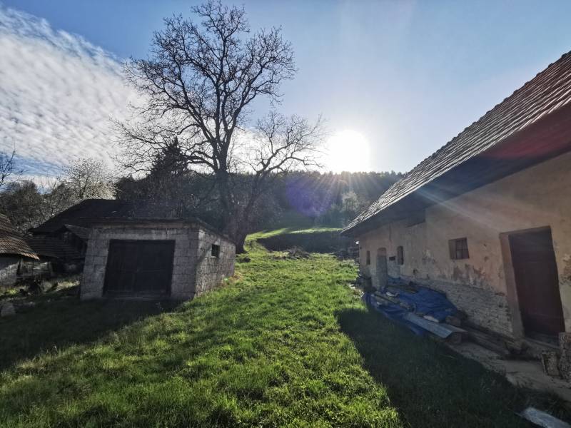 Travnatý pozemek s rodinným domem a starou garáží na Nitrianské ulici v Nitrianských Sučanech.
