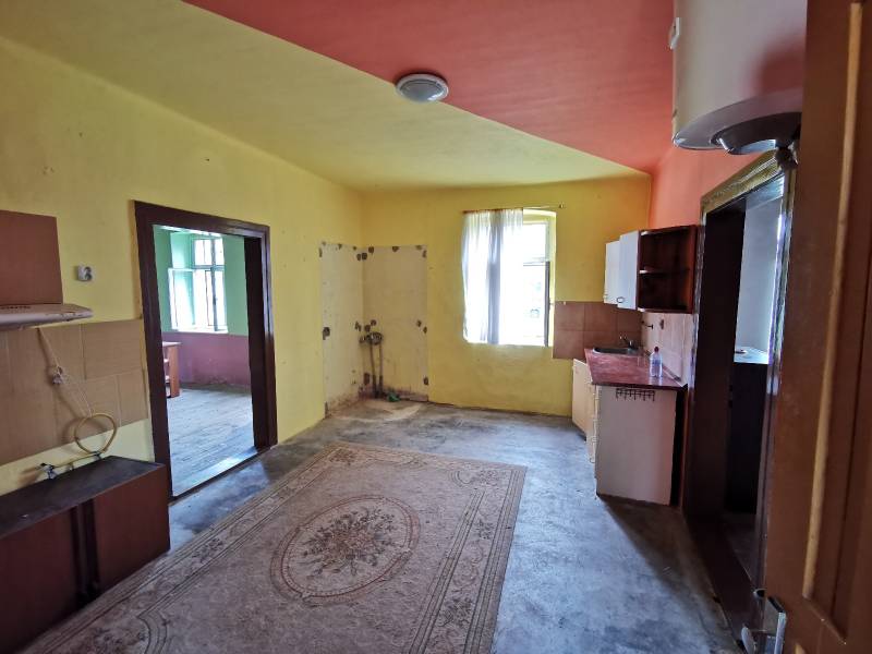 Interiér rodinného domu s kuchyňskou linkou a dveřním otvorem na různobarevné stěny.
