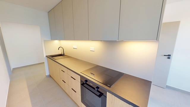Kuchyně v 2pokojovém bytě s moderní pracovní deskou a vestavěnými spotřebiči.