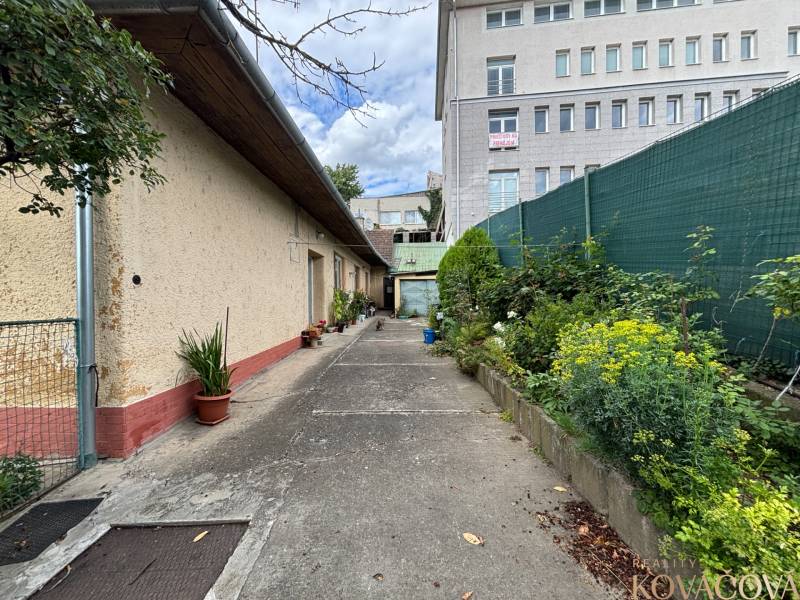 Exteriér rodinného domu v Ilave s uličkou a výhledem na vyšší budovu.