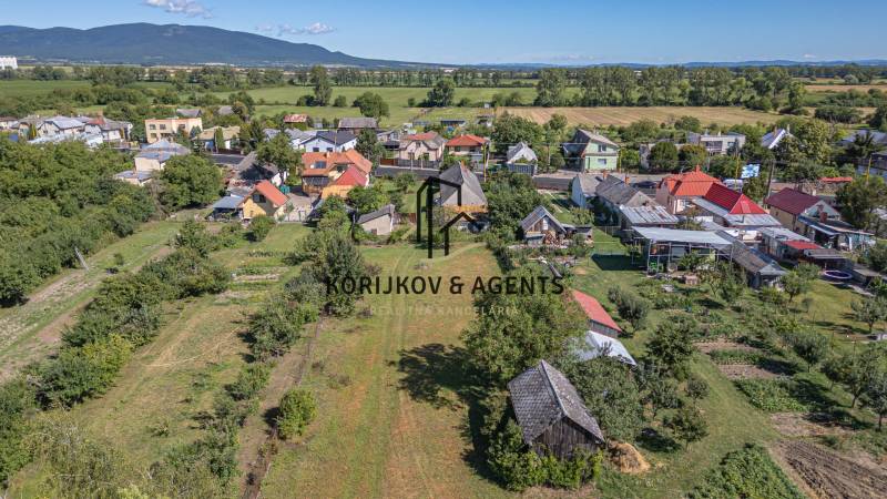 Letecký pohled na obecní pozemky na bydlení v Sečovcích obklopené zelení a domy.