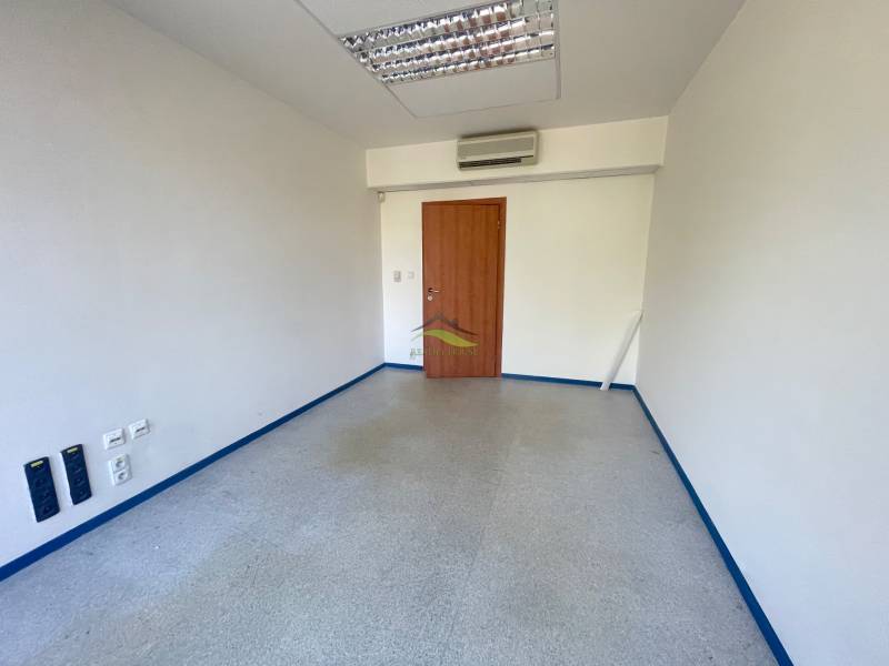 Prázdná kancelář s dřevěnými dveřmi, klimatizací a podlahou ve světlých odstínech.