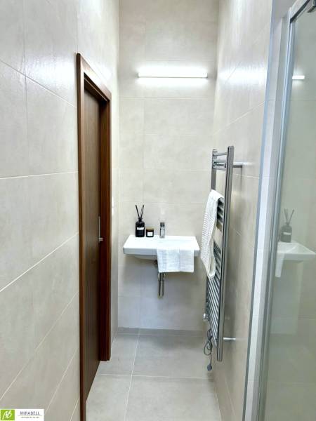 Koupelna s umyvadlem a osvětlením v 2-pokojovém bytě, s minimalistickým designem.