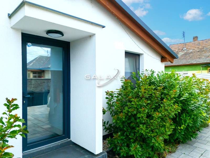 V Černé Vodě se nachází rodinný dům s bílou fasádou obklopený zelenými keři.