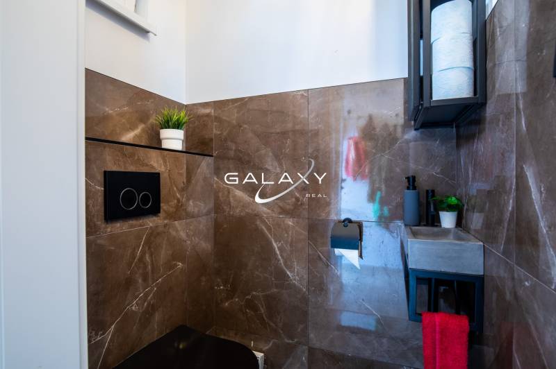 Koupelna v rodinném domě s hnědými obklady a praktickým úložným prostorem.