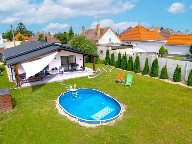 Rodinný dům v Černé Vodě s bazénem na zeleném trávníku a terasou.