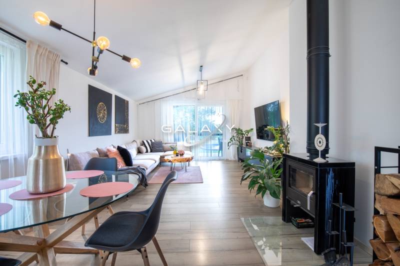 Obývací pokoj rodinného domu s krbem, pohodlnou pohovkou a skleněným stolem.