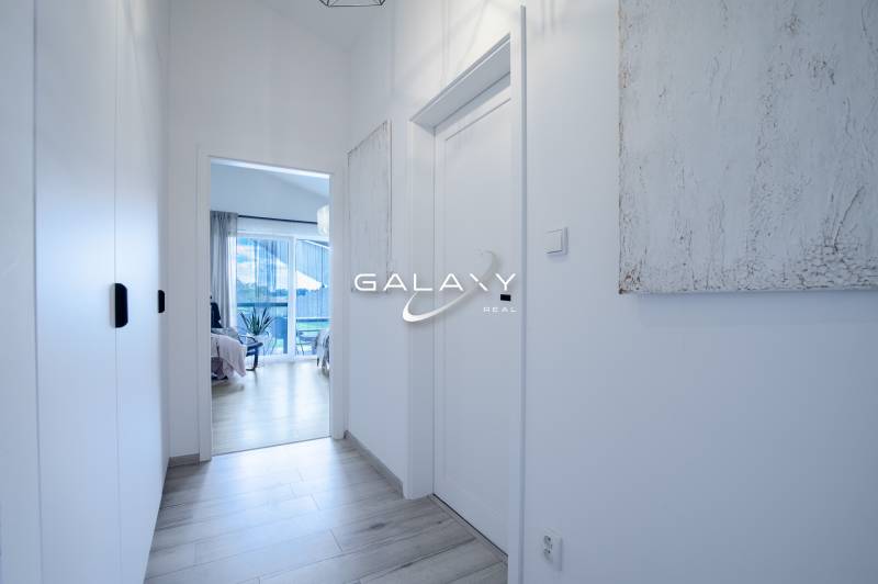 Úzká světlá chodba v rodinném domě s výhledem na pokoj a terasu.