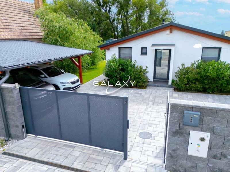 Rodinný dům v Černé Vodě s autem, bránou a upravenou zahradou.