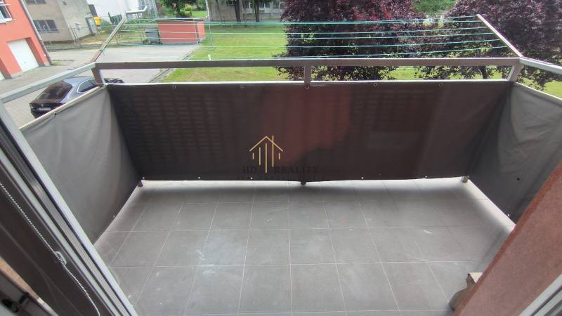 Balkon s dlážděnou podlahou a výhledem na zeleň v 2-pokojovém bytě Liptovského Mikuláše.