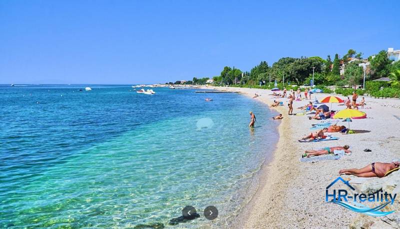 Pláž v Novalji s turisty relaxujícími u moře.