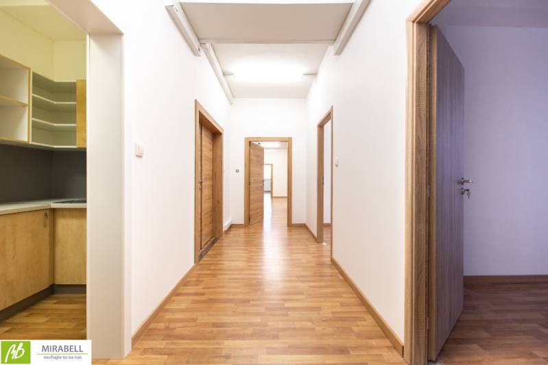Chodba s dřevěnou podlahou a dveřmi v kanceláři.
