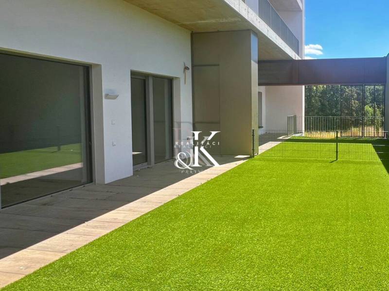 Terasa s umělým trávníkem a posuvnými dveřmi Rekreačního apartmánu v Banke.