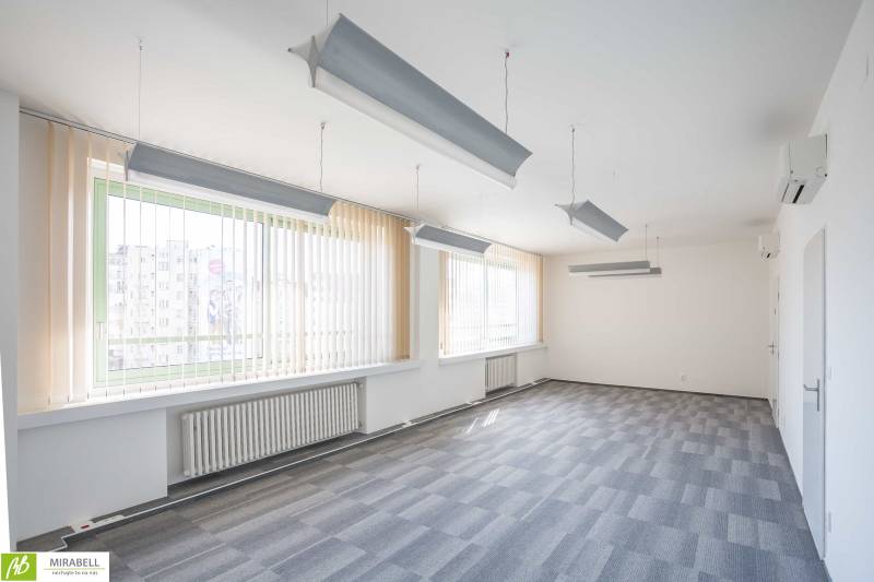 Prostorné kanceláře se závěsnými svítidly a vertikálními žaluziemi.