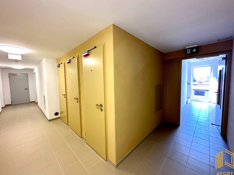 Chodba s více dveřmi v 2-pokojovém bytě, světlá dlažba a nouzový východ.