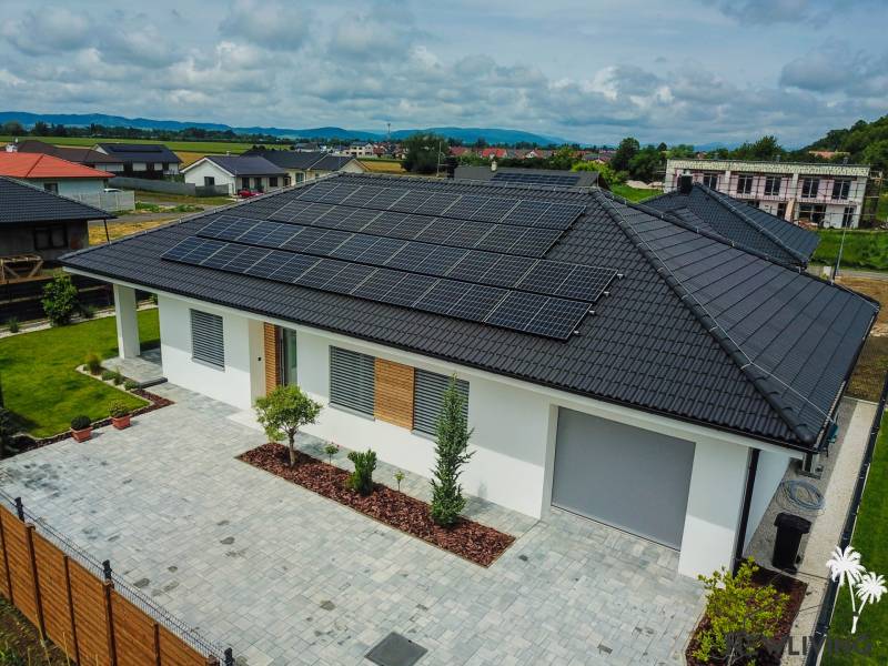 Rodinný dům v Piešťanech s fotovoltaickými panely na střeše obklopuje zelená zahrada.