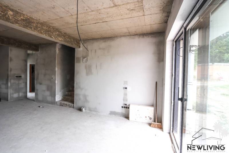 Interiér nedokončeného rodinného domu, betonové stěny a schody vedou do patra.