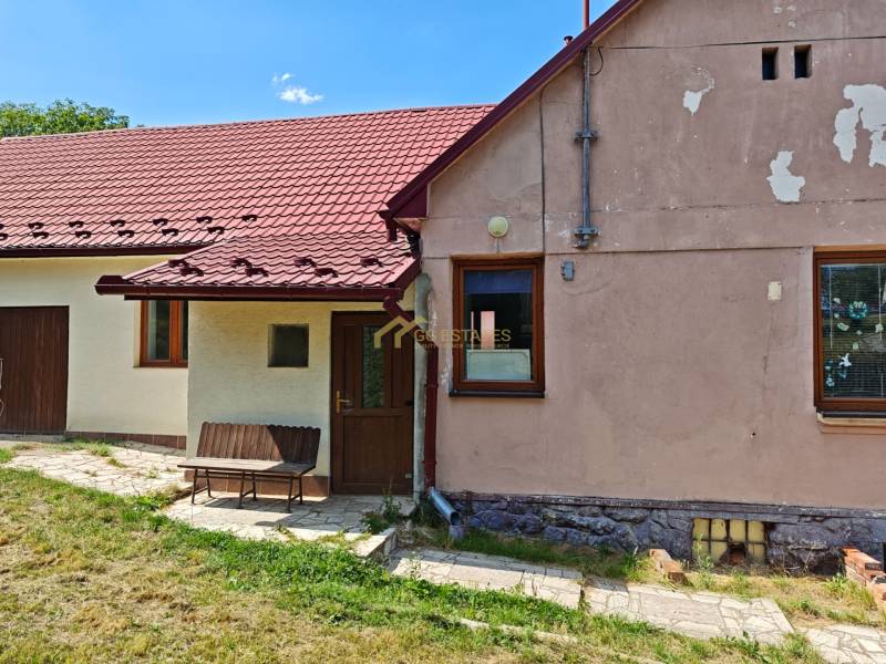 Rodinný dům na Dlouhé ulici ve Vranově nad Topľou s červenou střechou a lavičkou.