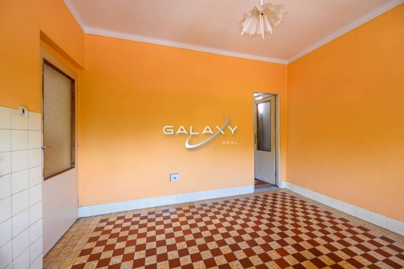 Pokoj v rodinném domě s oranžovými stěnami a dlaždičkovým vzorem na podlaze.