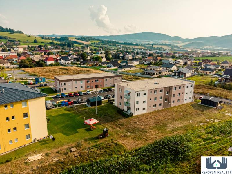 Výstavba bytů v Kriváni obklopená krajinou a rodinnými domy.