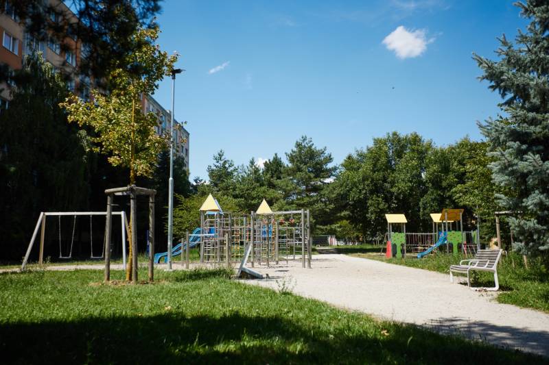 Dětské hřiště obklopené zelení a paneláky, Košice - městská část Jih.