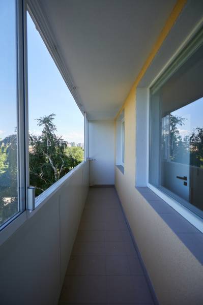Zasklený balkon v 2-pokojovém bytě s výhledem na zeleň.